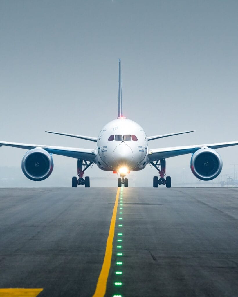 Front view of Indigo airplane taxiing on a runway with landing lights on.