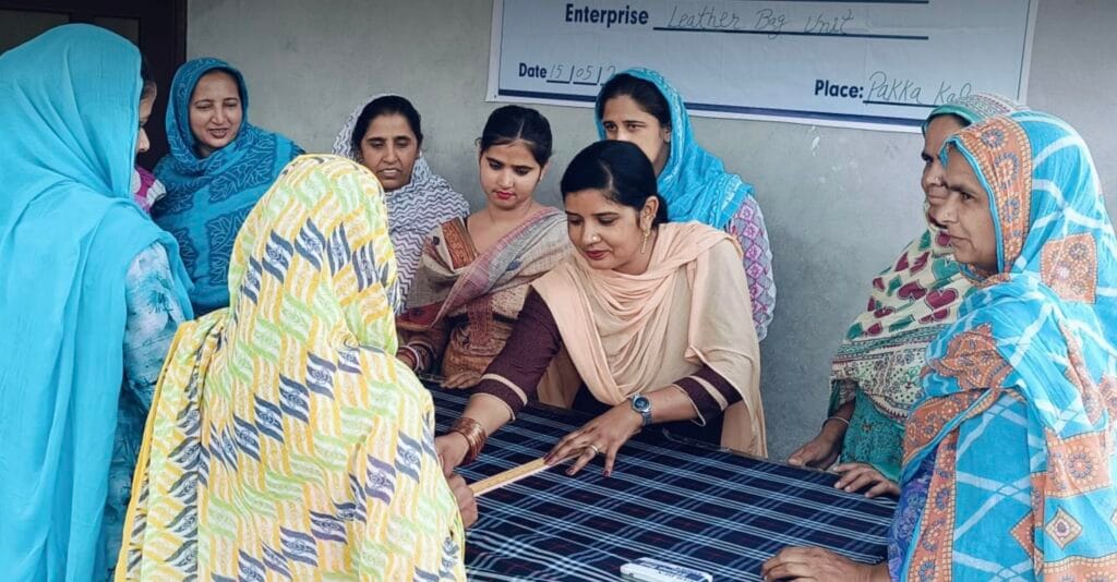 Group of women gathered around a table, measuring and examining fabric during a community workshop.